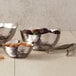 Three American Metalcraft hammered stainless steel bowls with nuts and olives in them.