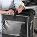 A chef using a Vollrath 5-Series delivery backpack bag on a counter in a professional kitchen.