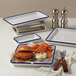 An American Metalcraft blue speckled melamine serving tray with a burger, fries, and a drink on a table.