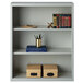 A light gray Hirsh 3-shelf bookcase with books and a box on top.