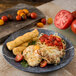 A Carlisle Ridge soapstone melamine dinner plate with chicken and tomato pasta and breadsticks.