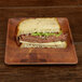 A sandwich with meat and lettuce on a checkered bamboo melamine plate.