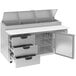 A stainless steel counter with three open drawers.