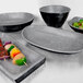 A rectangular coal melamine serving platter with bowls of food on it.