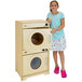 A little girl standing next to a Whitney Brothers natural wood play washer and dryer.