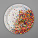 A white paper plate with confetti sprinkles on it.