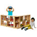 Two children playing with a Whitney Brothers toddler-height storage cabinet filled with toys.