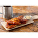 A rectangular faux oak wood melamine display board with pretzels and mustard on it.