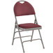 A burgundy metal folding chair with a padded fabric seat.