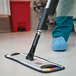 A person using a Rubbermaid Executive Series microfiber mop frame to clean a floor.