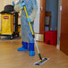 A person in a protective suit using a Rubbermaid Quick-Connect telescopic pole to mop the floor.