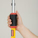 A hand holding a yellow and black Rubbermaid Quick-Connect telescoping handle.