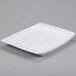 A white rectangular tray with a small square cut out on a gray surface.