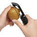 A person using an OXO straight vegetable peeler to peel a kiwi.