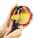 A person using an OXO serrated vegetable peeler to peel a peach.