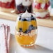 A customizable Acopa stemless wine glass filled with fruit and whipped cream.