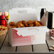 A red plaid barn take-out lunch box filled with fried chicken on a table.