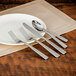 A white plate with a Walco Vestige stainless steel dinner knife and fork on it.