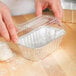 A person's hand placing dough into a clear plastic dome lid.