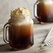 A glass mug of DaVinci Gourmet Classic Caramel Pecan flavoring syrup-infused coffee with whipped cream on top.