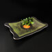 A rectangular melamine platter with a pine cone pattern on it with a green plant on it.