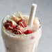 A glass of milkshake with a straw and raspberries made with DaVinci Gourmet Classic White Chocolate Flavoring Syrup.
