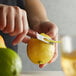 A person using a Victorinox channel knife with a rosewood handle to peel a lemon over a counter.