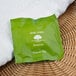 A green Basic Earth Botanicals shower cap packet on a white towel.