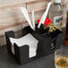 A black Choice bar caddy with napkins, straws, and a glass of alcohol.