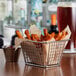 A rectangular mini fry basket filled with fries and a glass of beer.