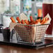 A rectangular chrome mini fry basket filled with fries and ketchup.