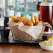 A chrome rectangular mini fry basket filled with fried food on a table in a seafood restaurant.