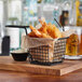 A black rectangular mini fry basket filled with fried shrimp on a wooden board.