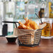 An Acopa black wire rectangular mini fry basket with fried shrimp and a drink on a table.