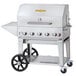 A stainless steel Crown Verity mobile barbecue grill with wheels and a stainless steel top.