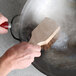 A person using a Thunder Group Palmyra bristled wok brush to clean a pan.