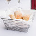 An American Metalcraft chrome square basket with bread rolls inside on a table.