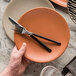 A hand holding a plate with a Reserve by Libbey European dinner fork and knife.