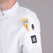 A person wearing a white Chef Revival chef jacket with a yellow pen in the pocket.