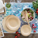 A table set with Bambu disposable bamboo plates and wooden utensils with a bowl of salad.