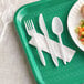 A green and white tray with a white wrapped plastic fork and knife.