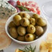 A white plate with a bowl of Belosa Jalapeno Stuffed Queen Olives and cheese.