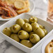 A bowl of Belosa jalapeno and garlic stuffed green olives on a table with bread.