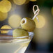 A Belosa martini with cream cheese and jalapeno stuffed green olives on a table.