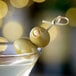 A close-up of a martini glass with Belosa garlic stuffed green olives in it.
