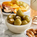 A bowl of Belosa cream cheese stuffed green olives and nuts on a table.