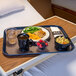 A Dinex dark blue Glasteel fiberglass tray holding a bowl of soup, a plate of food, and a bowl of berries on a table.