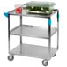 A Carlisle stainless steel utility cart with food on it and a container of green vegetables.