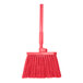 A close-up of a red Carlisle Sparta Duo-Sweep broom with a long plastic handle.