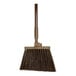 A brown Carlisle Sparta Duo-Sweep broom with a wooden handle and black bristles.